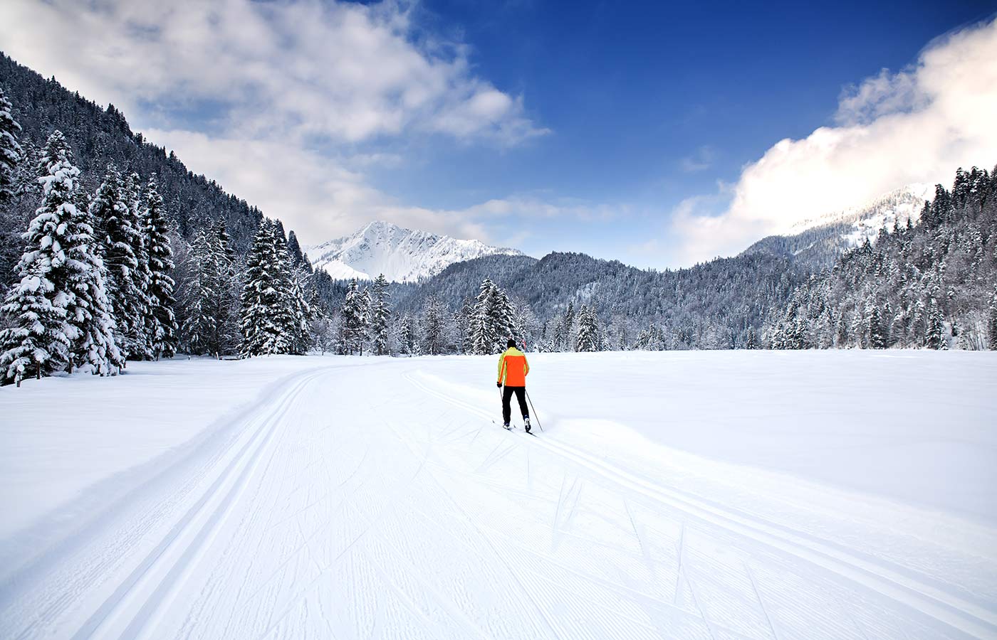 A cross-country skier along a track on a snowy mountain valley