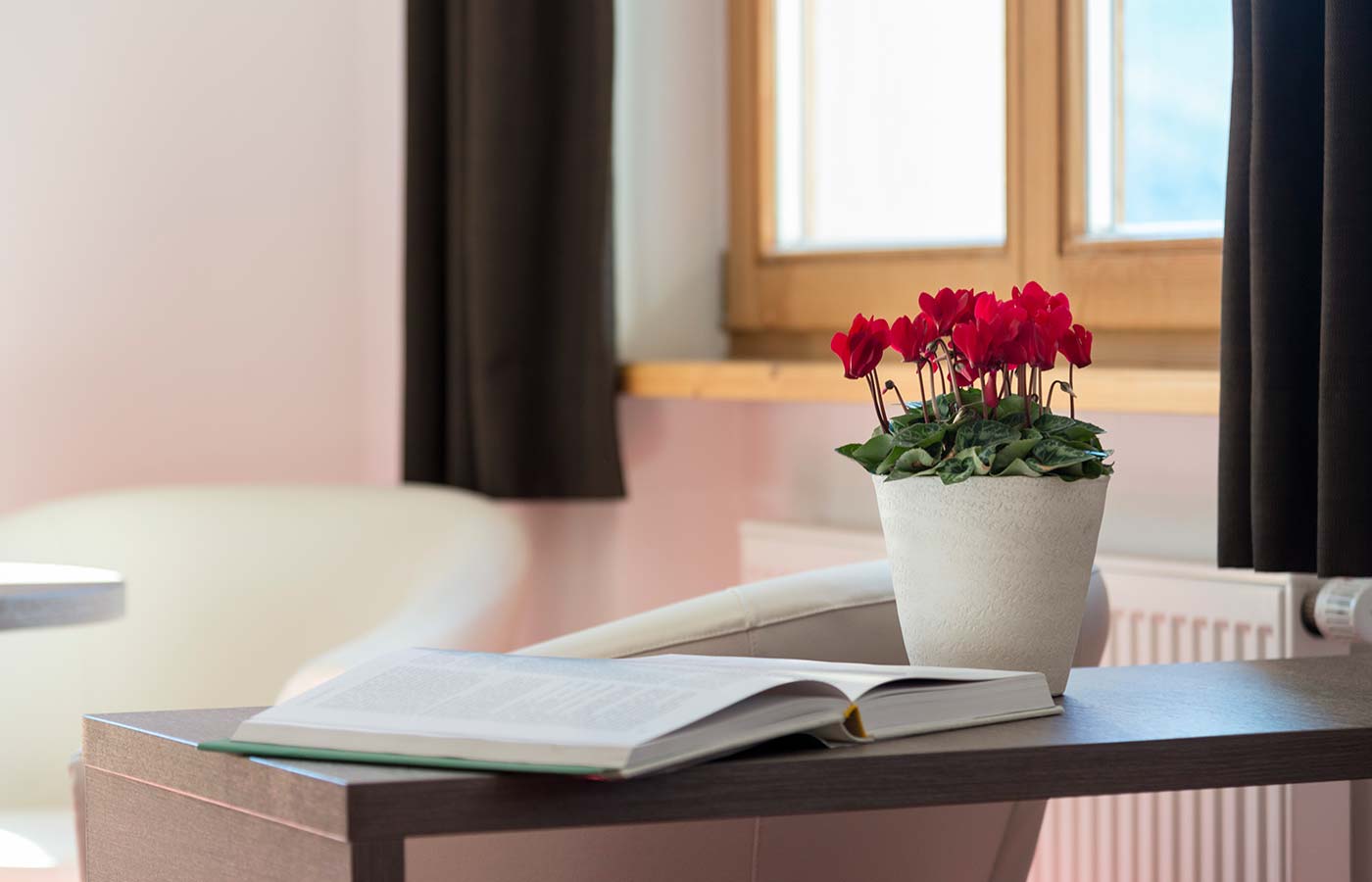 Vadi di fiori e libro aperto su un tavolino in una delle camere del Waldheim