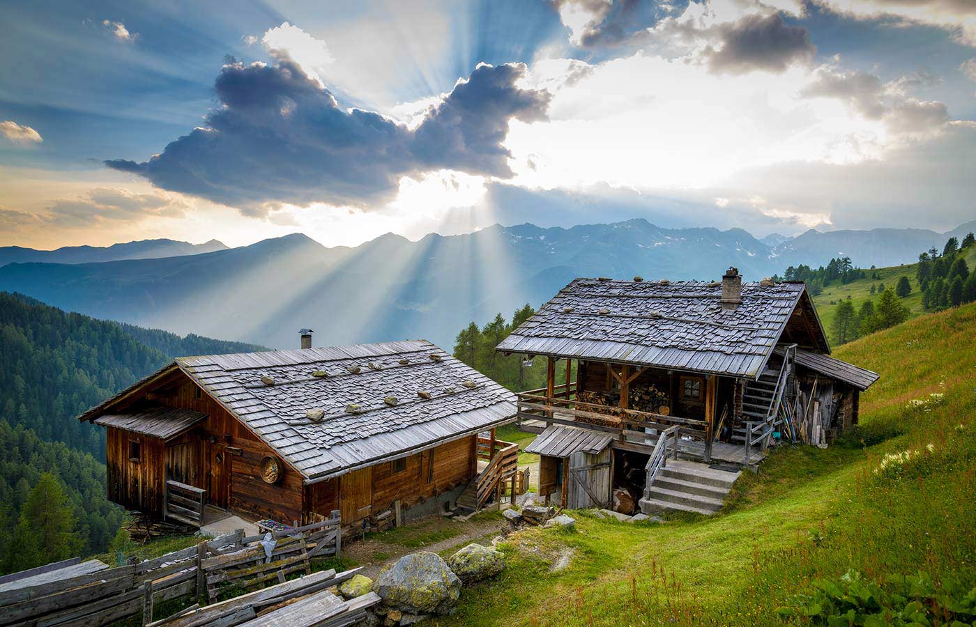 Due vecchi masi di montagna in legno illuminati dalla luce del sole nascosto dalle nuvole