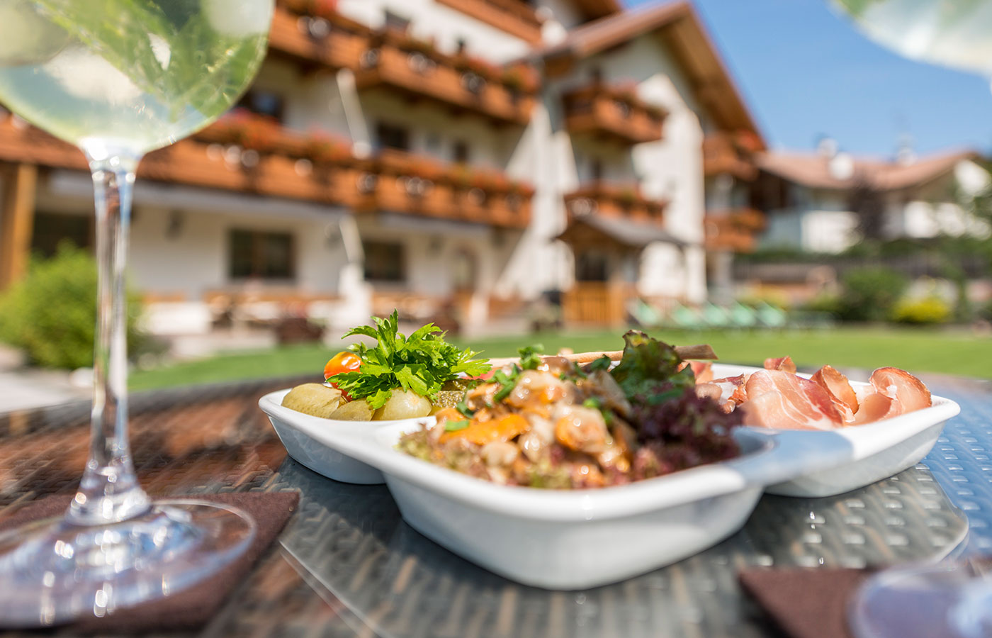 Nahaufnahme von einem Glas Hugo und Snacks zum Aperitif im Hotel Waldheim im  Hintergrund.