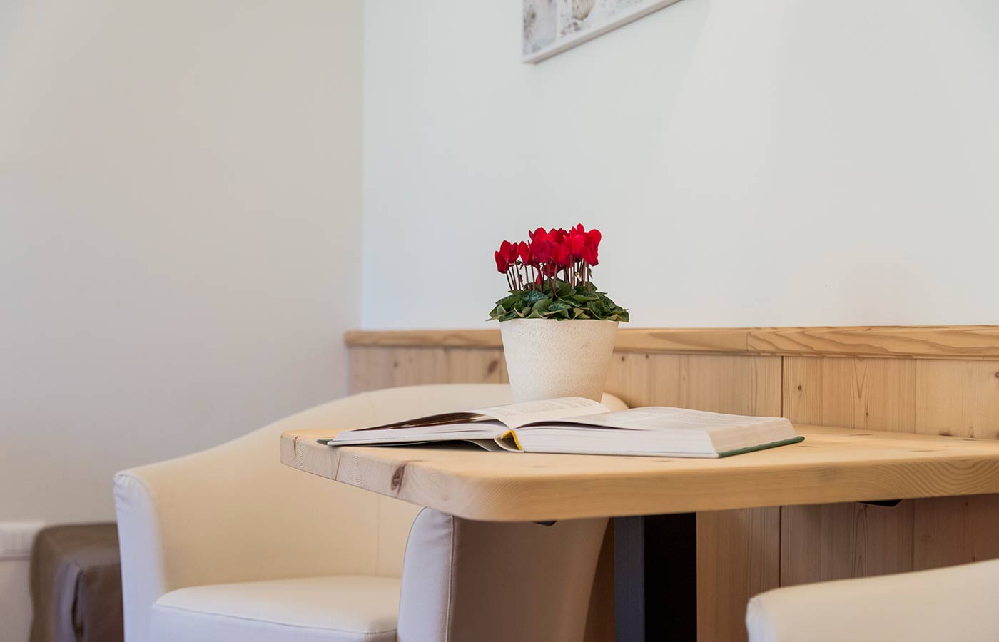 Wooden table with vase of flowers and open book in the room of Hotel Waldheim