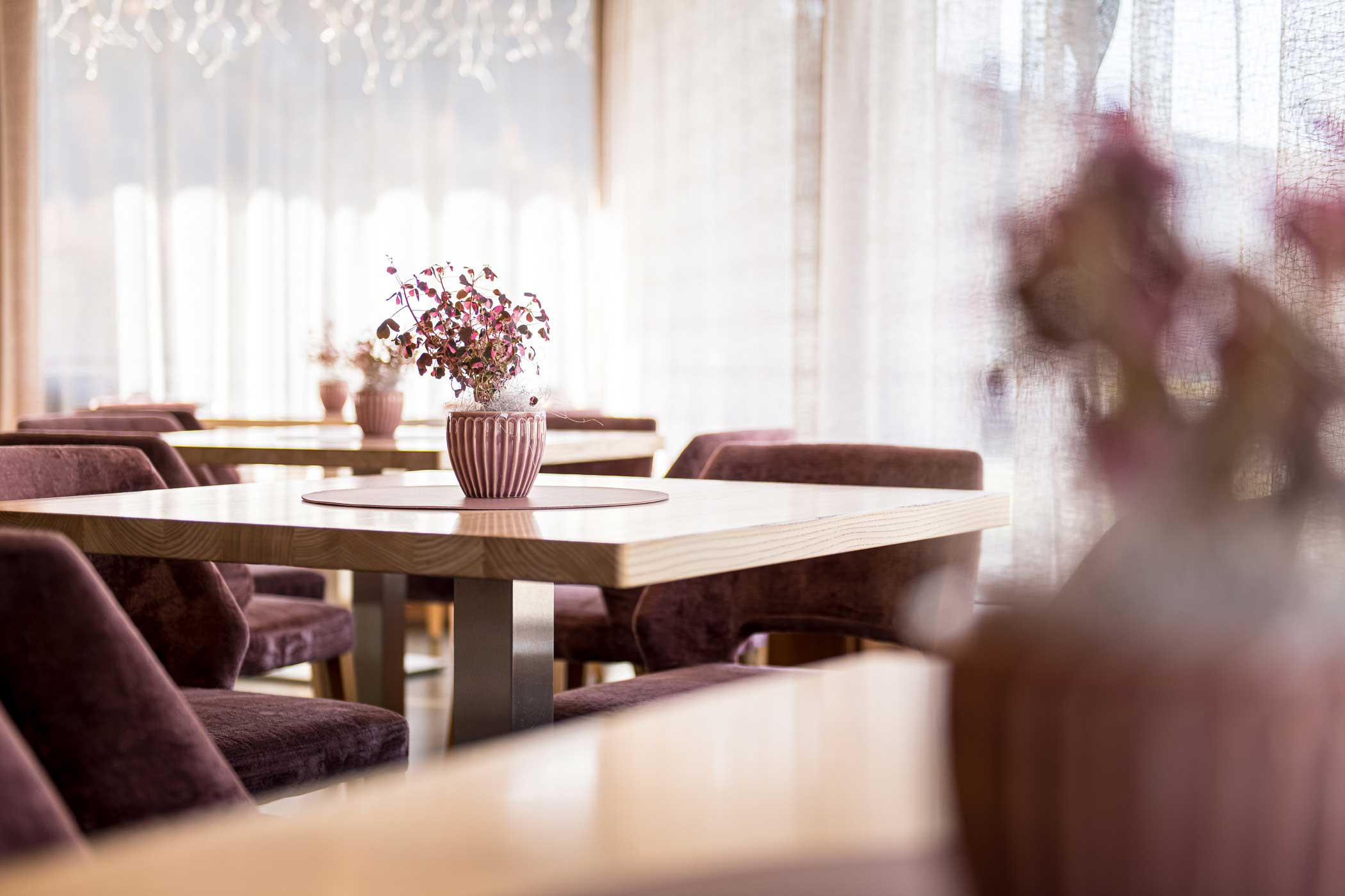 Gemütliches Restaurant mit Holztischen, lilafarbenen Stühlen und Vasen mit Trockenblumen als Tafelaufsatz. - Hotel Waldheim