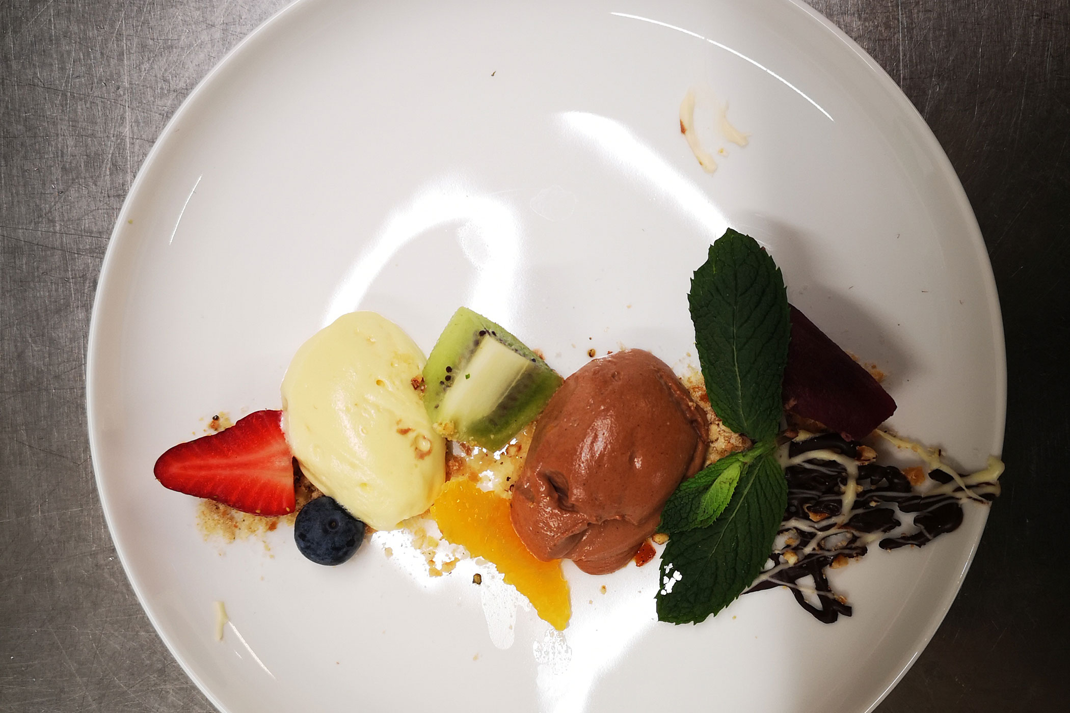 Zwei Schokoladenravioli mit Streuseln, serviert mit halbierten Erdbeeren auf einem weißen Teller. - Hotel Waldheim