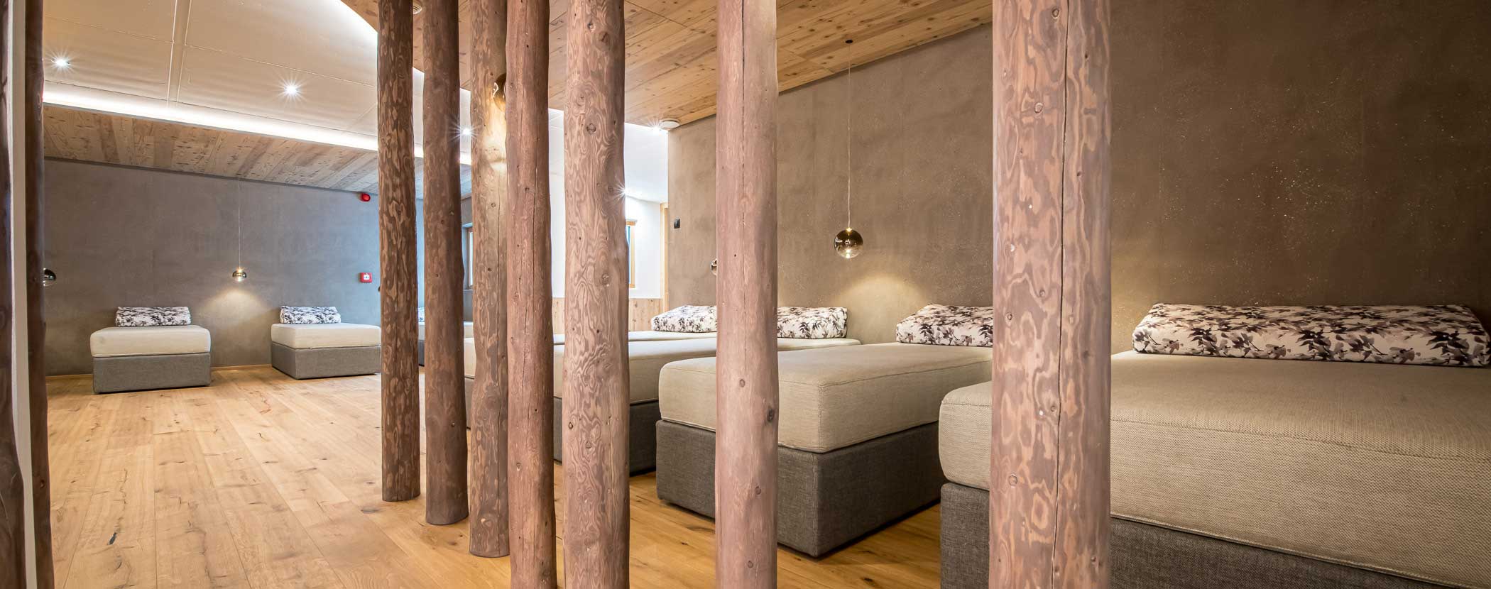 Ein gemütliches Zimmer mit Holzbalken, mehreren modernen Betten und sanfter Beleuchtung auf einem Holzboden. - Hotel Waldheim