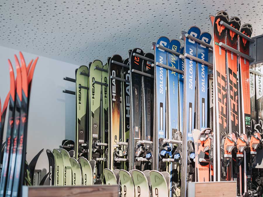 Mehrere Reihen von Skiern in verschiedenen Farben sind in einem Skiverleih oder -geschäft ordentlich aufrecht gestapelt. - Hotel Waldheim