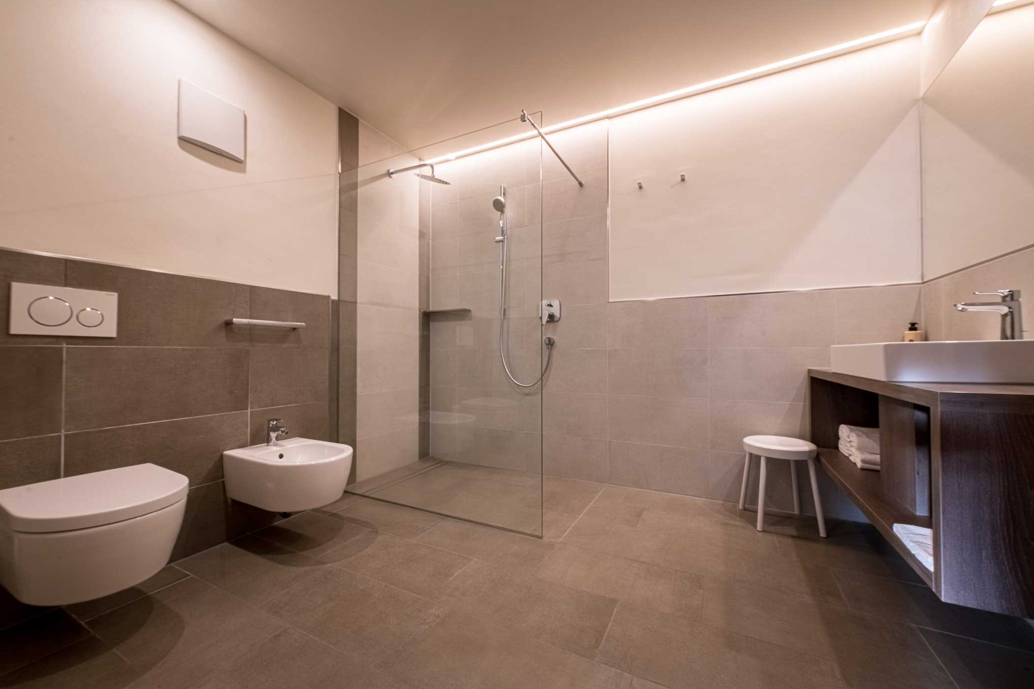 Modernes Badezimmer mit begehbarer Dusche, wandmontierter Toilette und Bidet, Waschbecken und minimalem Dekor. - Hotel Waldheim